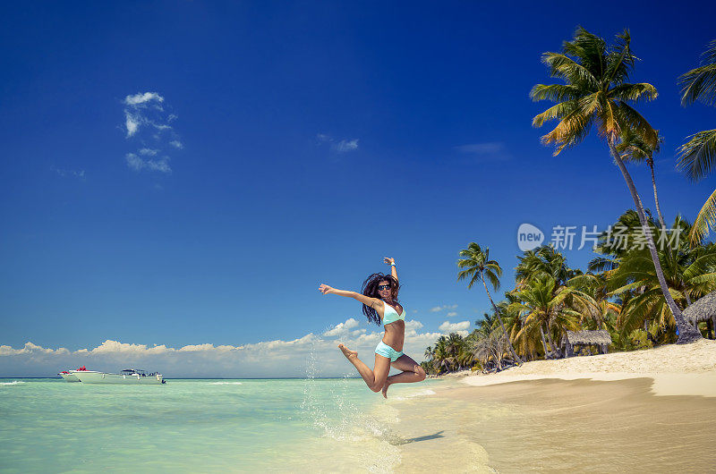 无忧无虑的年轻女子在热带海滩上跳跃