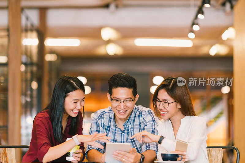 年轻的亚洲大学生或同事一起在咖啡店使用平板电脑，多元化的群体。休闲业务，自由职业者的工作在咖啡馆，社会会议，或教育概念