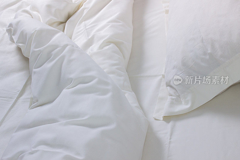 白色的床上用品的背景。皱巴巴的被褥，背景，灯光效果。