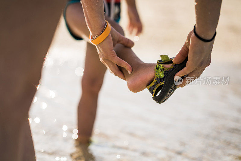 近距离观察一位面目全非的母亲在海上帮助她的孩子穿鞋。