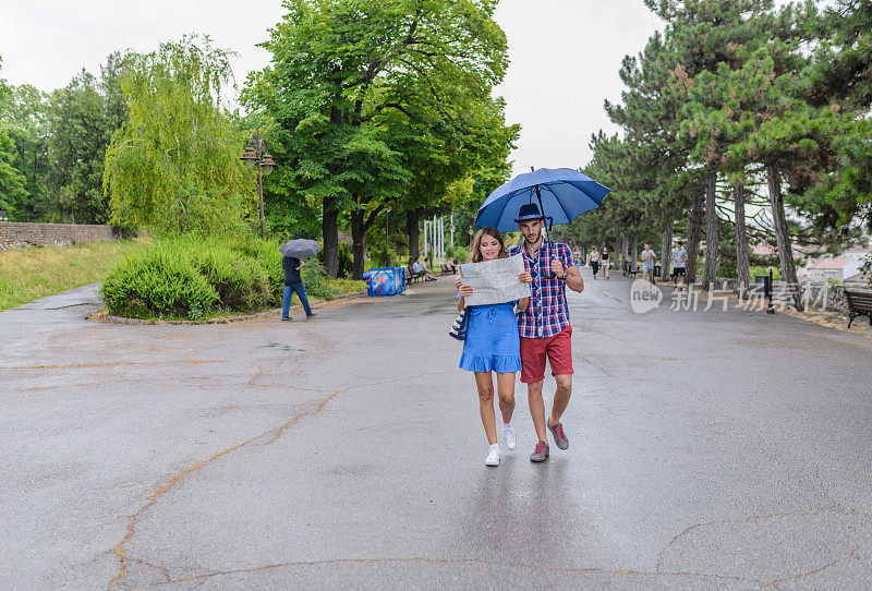 一对年轻的游客在雨天在城市里寻找乐趣