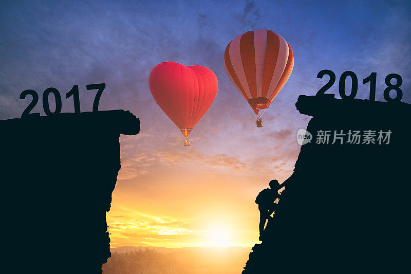 2017年至2018年间，一名年轻人乘坐两个热气球登山。新年快乐概念