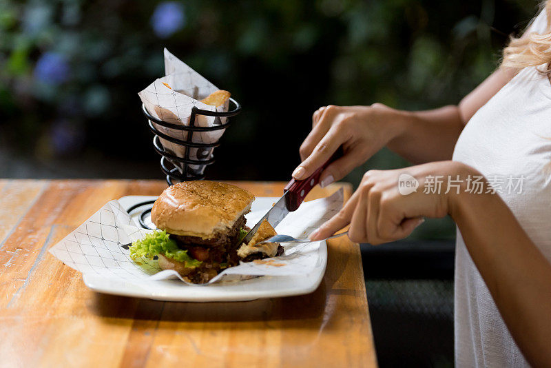 一个女人在餐厅吃汉堡包的特写镜头