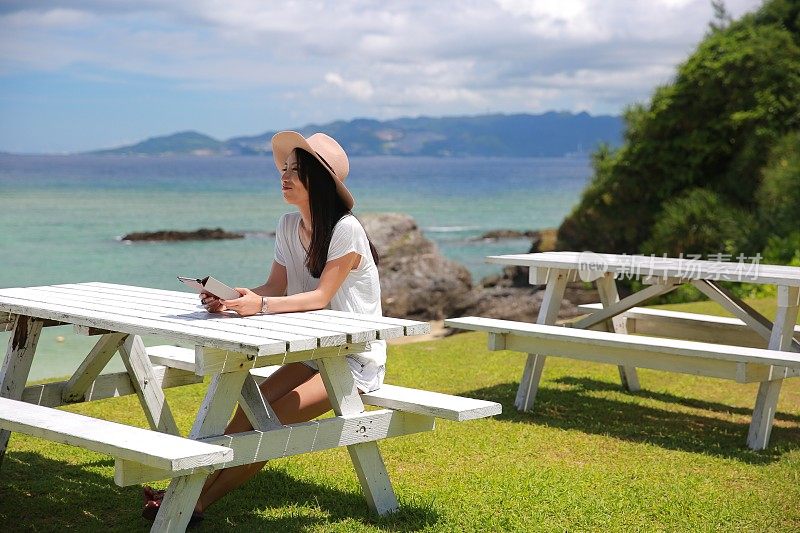 一位年轻的日本妇女在一张白色的长凳上等候。