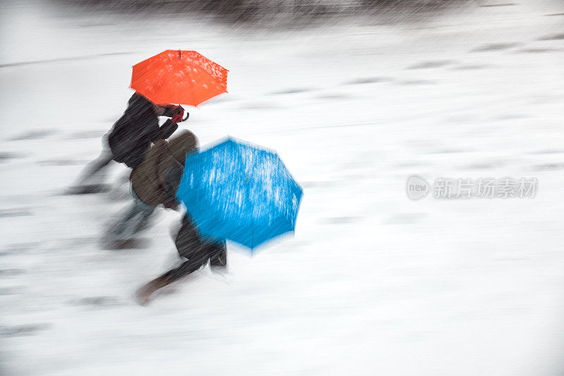 一群人撑着雨伞在暴风雪中行走