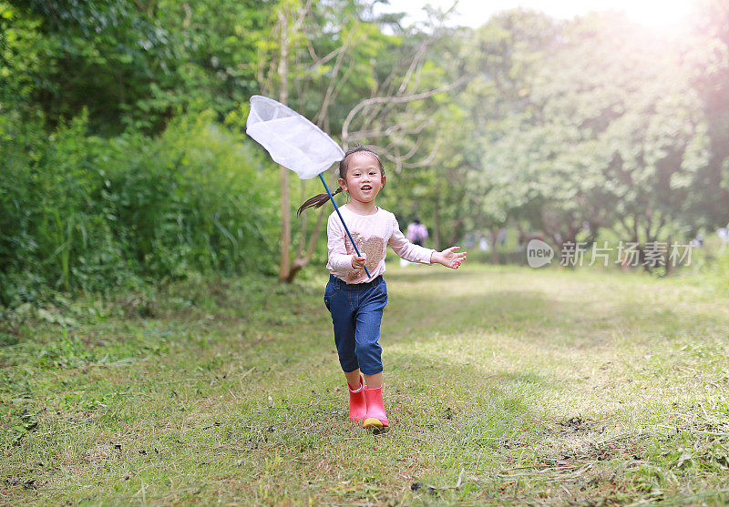 快乐的亚洲小女孩在田野里玩在夏天的昆虫网。