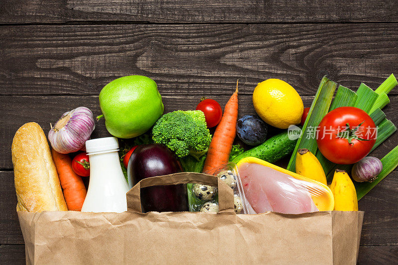 满纸袋不同的健康食品在乡村木质背景