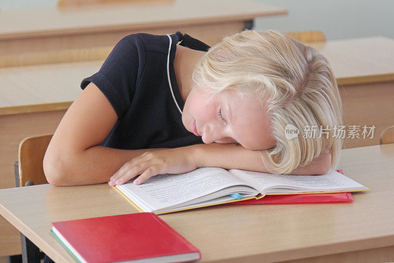 疲惫的女学生在教室的课桌上睡觉