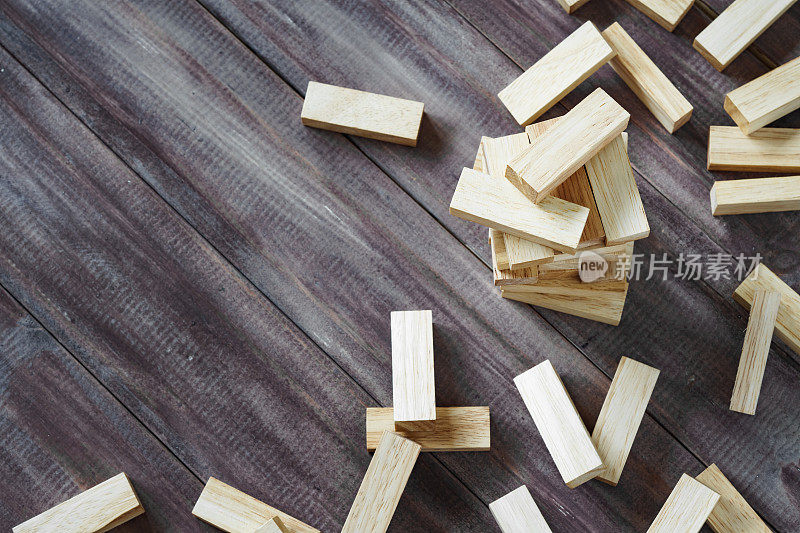 撞击的木制积木塔在深色的木材背景与复制空间。崩溃木块堆叠游戏背景概念为商业风险，不平衡，崩溃，破坏和错误