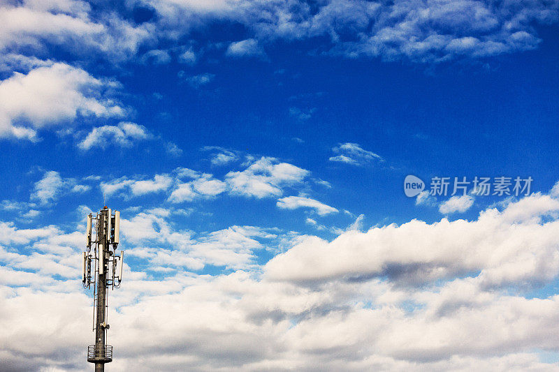 移动电话基站天线对着一个部分多云的夏季天空