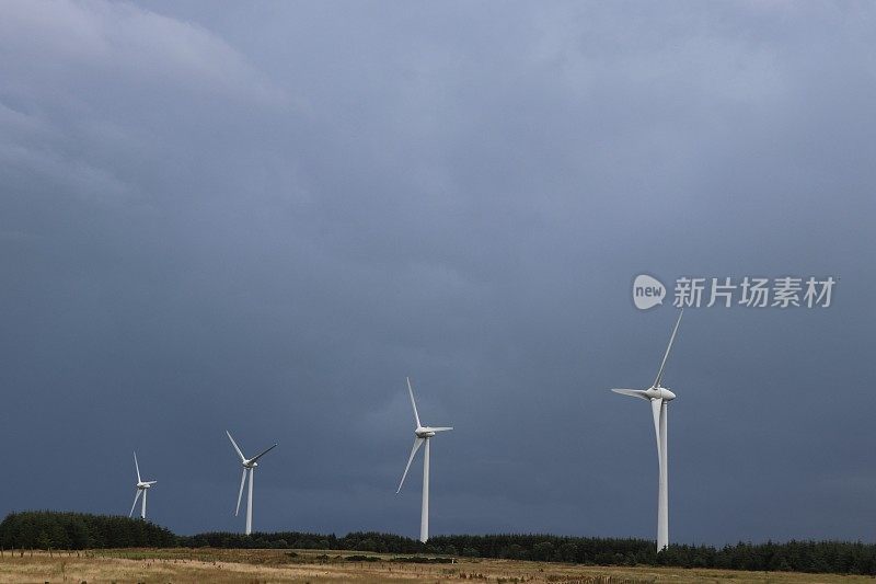 四个风力涡轮机对抗暴风雨的蓝天和复制空间