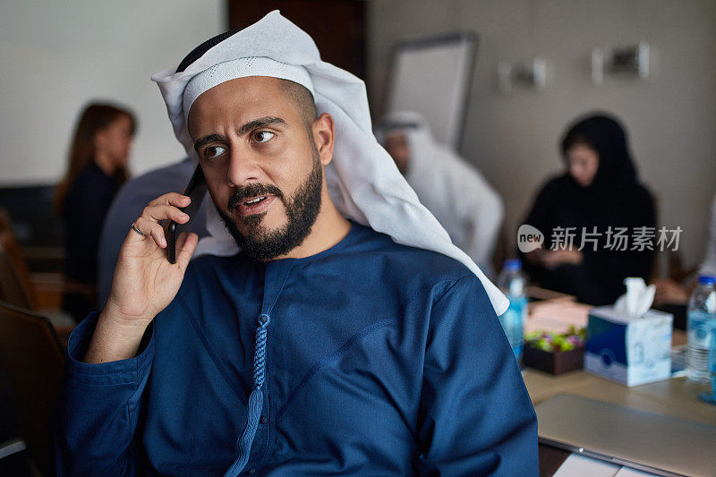 一位阿联酋高管在办公室里用智能手机聊天