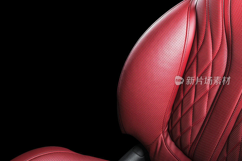 汽车内部的红色皮革。穿孔皮革舒适座椅与缝线隔离在黑色背景。汽车内饰的细节。汽车详细。汽车内部