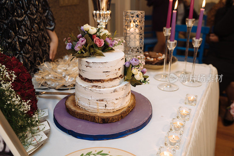 烹饪、甜蜜、婚礼理念。近距离两层神奇的蛋糕与白色和棕色的地毯和装饰鲜花