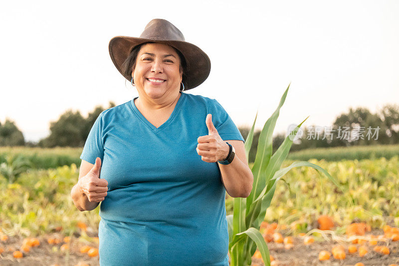 微笑骄傲的农民在他的南瓜农场摆姿势