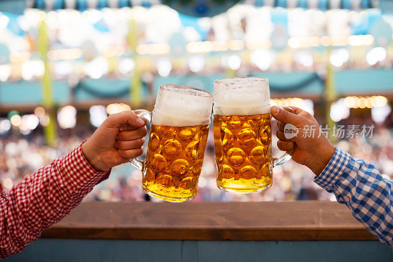 两个人在啤酒节的啤酒帐篷里用啤酒杯敬酒