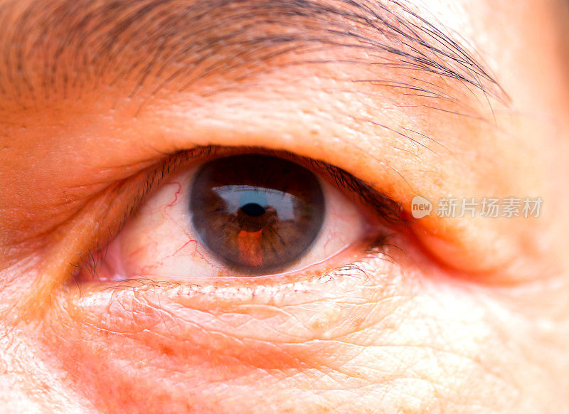 宏观的眼睛，特写美丽的中年亚洲男人与黑色的眼睛。眼睛里的血管。