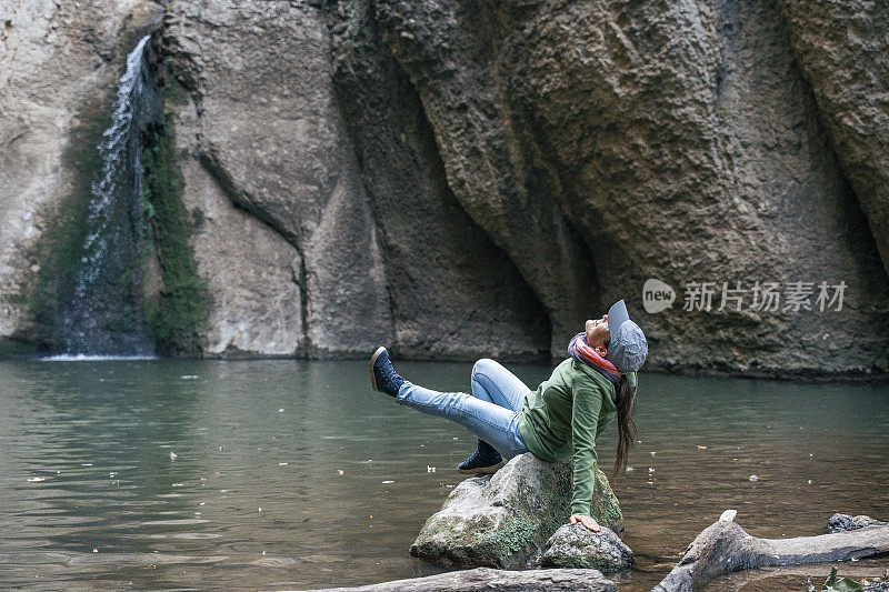 回归自然。独自在瀑布附近旅行。一个快乐的年轻女游客漫步在大自然中。阳光明媚的户外享受。