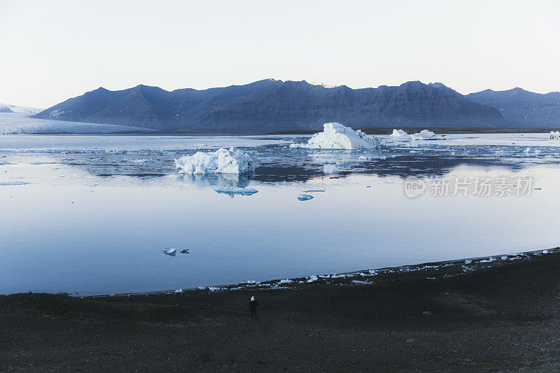 在冰岛的Jokulsarlon冰川泻湖附近的湖岸行走的女人