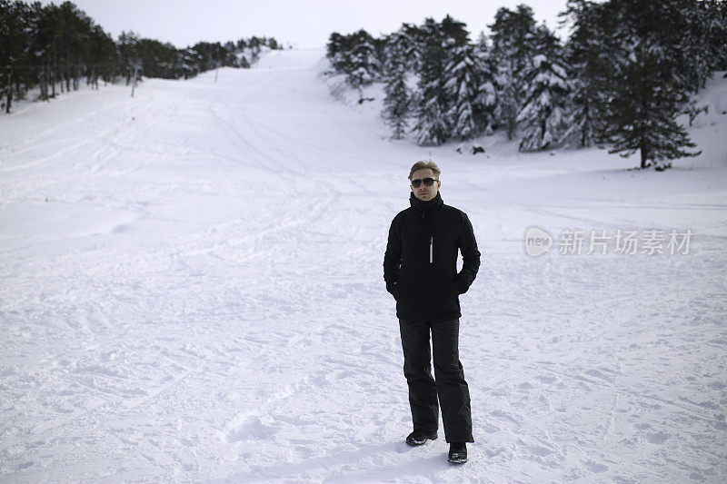 有魅力的戴眼镜的金发男人在雪地里的肖像