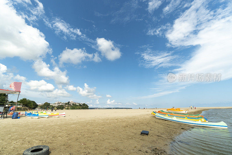 在一个美丽的夏日，五颜六色的独木舟等在湖边