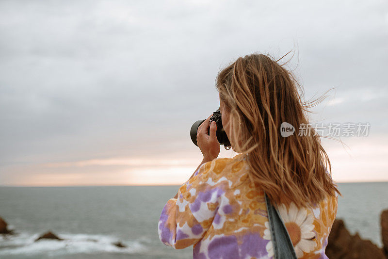 在海边用单反相机的年轻女子
