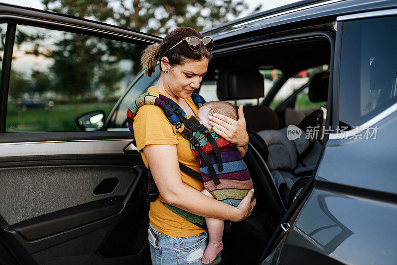 妇女把婴儿放在婴儿座椅上并系好安全带。宝宝活泼可爱。