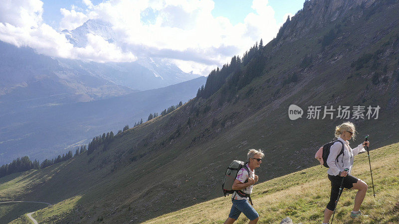 鸟瞰图的徒步旅行夫妇穿越高山草地，在日出