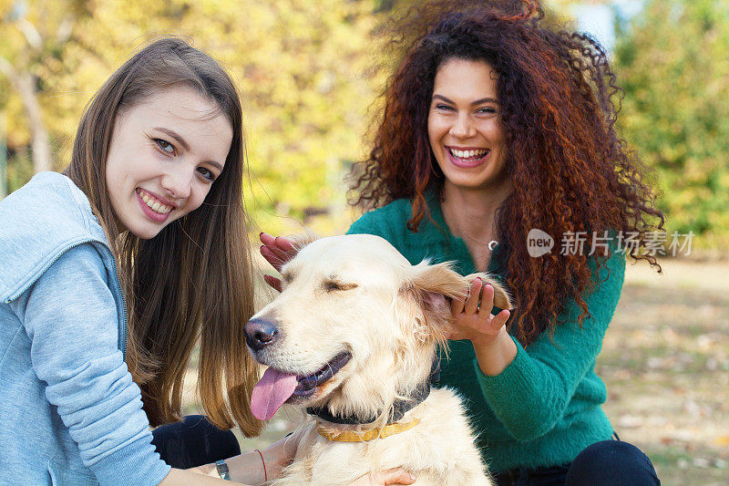 两个女孩在玩一只狗