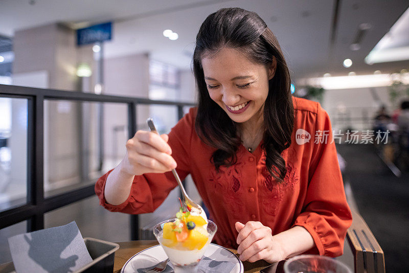 快乐的年轻女子在咖啡馆吃糖果