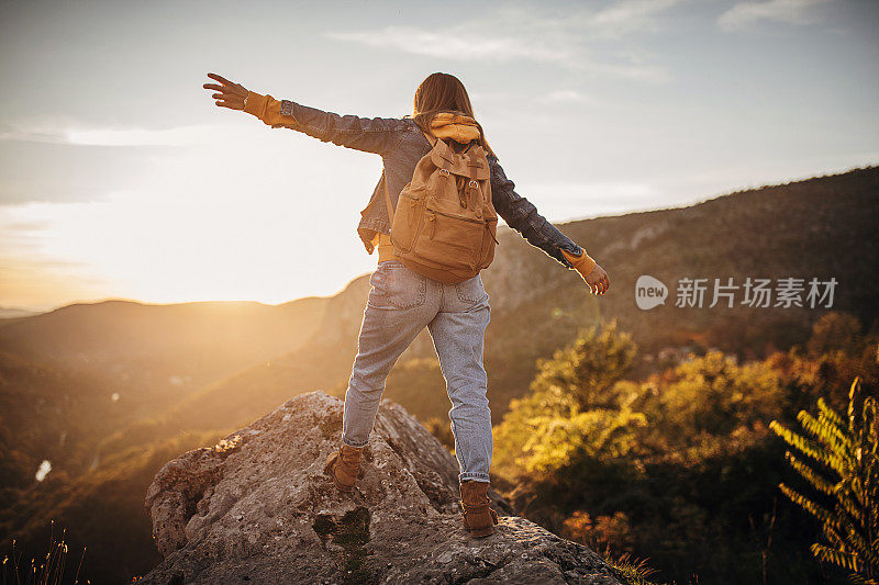 一个年轻的女人在山顶行走时保持着平衡