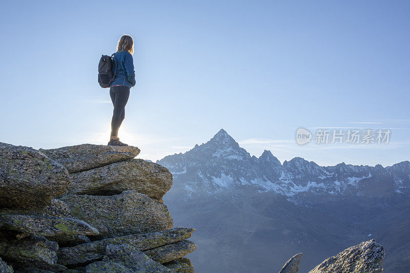 清晨，女徒步旅行者在阳光明媚的山脊上放松