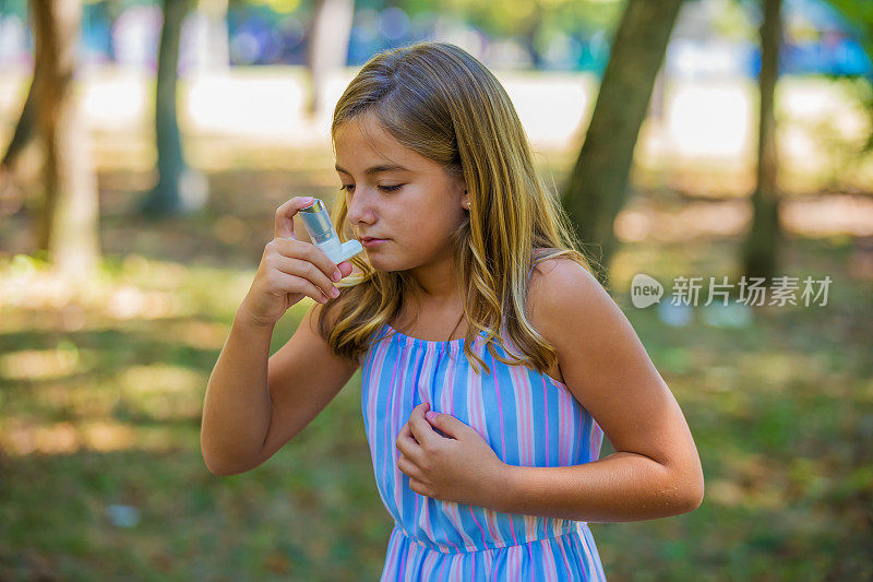一个可爱的女孩在公园里使用哮喘吸入器。