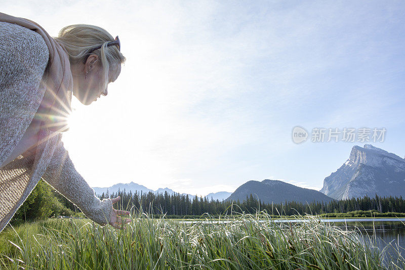 一个女人手牵着手穿过湖岸的高草