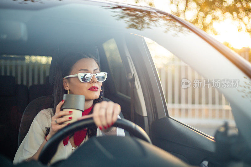 一个年轻开朗的女人喜欢一辆新车，坐在车里。喝咖啡休息时间