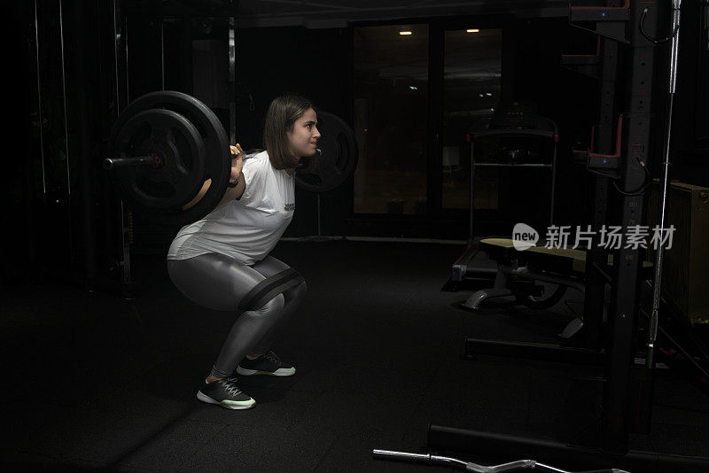 年轻的女健美运动员在做举重运动。