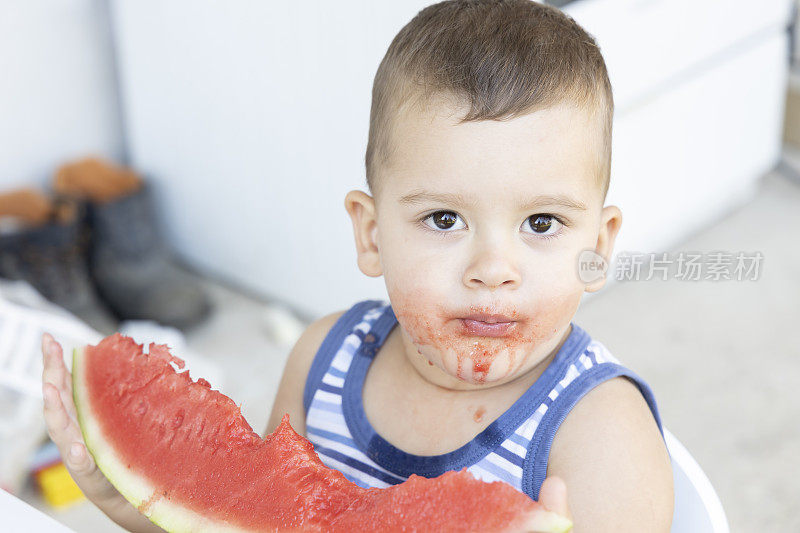 小可爱的男孩在外面的花园里吃西瓜。夏天的乐趣和健康的食品，为年轻的孩子。