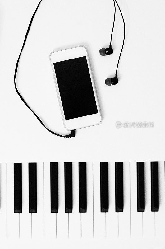 钢琴键和音乐播放设备与耳机。黑白照片。