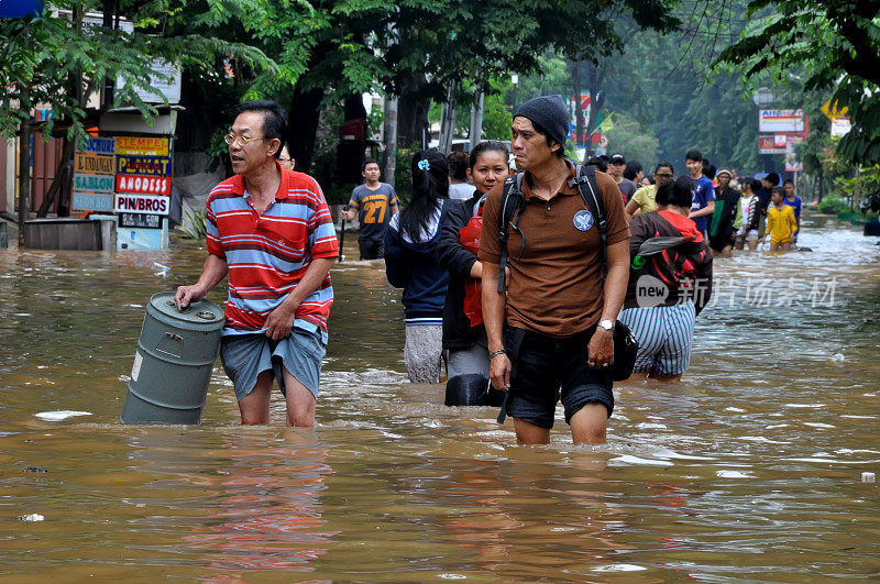 印度尼西亚雅加达的居民正在穿过被洪水淹没的道路，雅加达的几条道路在暴雨后被洪水淹没。