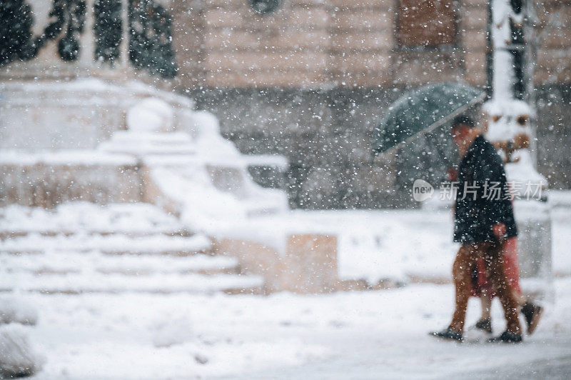 一对夫妇在下雪天撑着伞散步