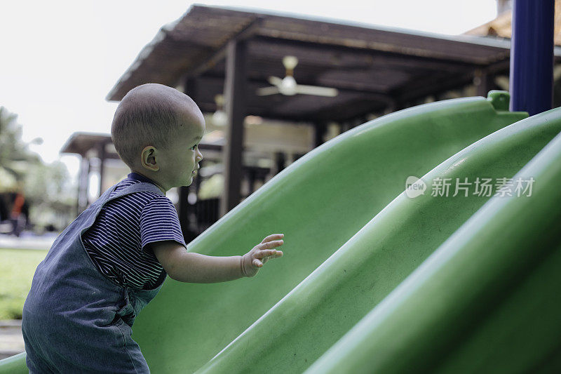 一个小男孩在操场上玩滑梯