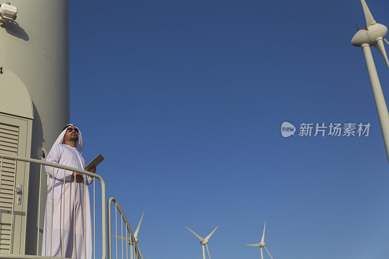 中东商人在农场的风力涡轮机上