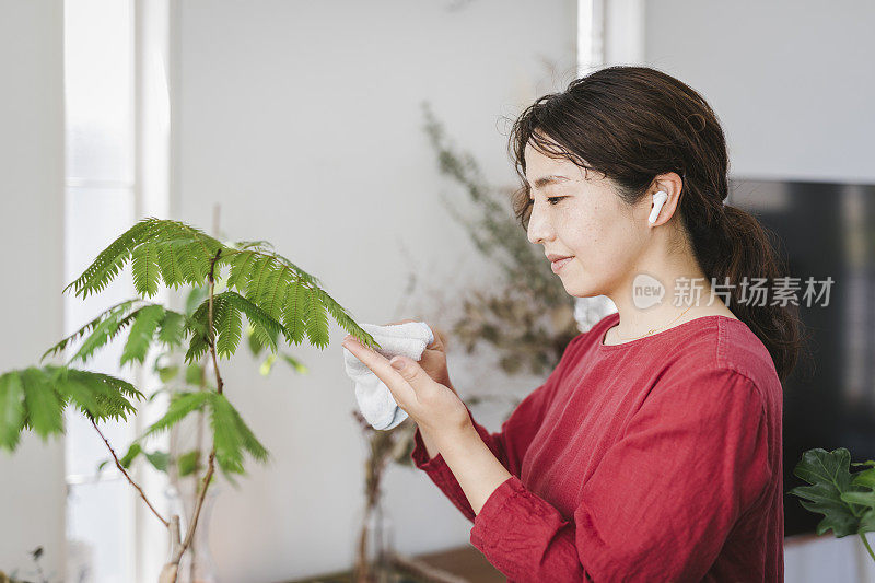 女人在家用无线耳机听音乐和园艺