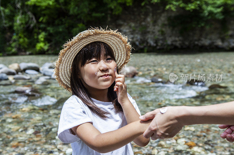 亚洲妈妈在河边给女儿涂防晒霜