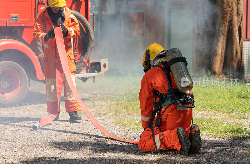 消防队员或消防队员在事故模拟训练中使用灭火器和从软管喷射高压水时保持橡胶消防水管。