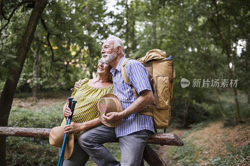 一对老夫妇背着背包徒步旅行的照片