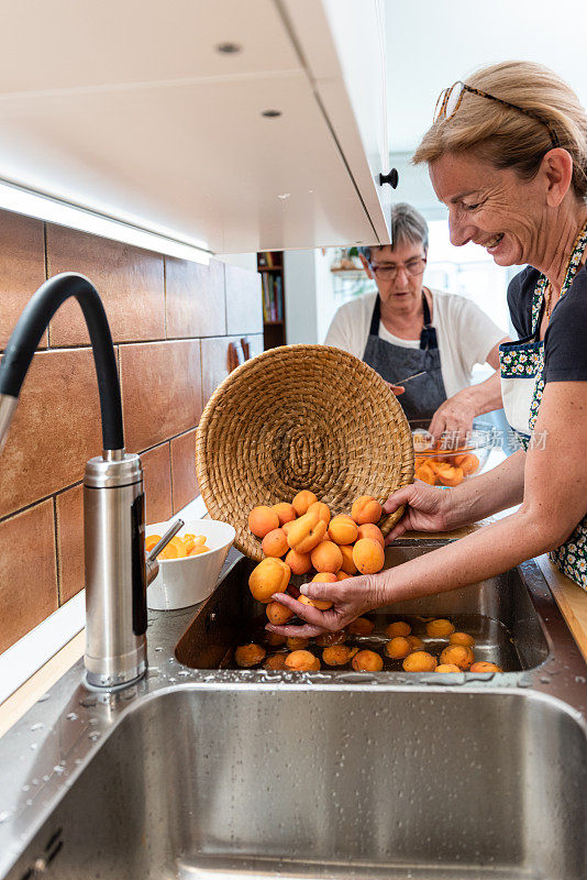 家庭厨房中洗杏自制果酱的两代妇女
