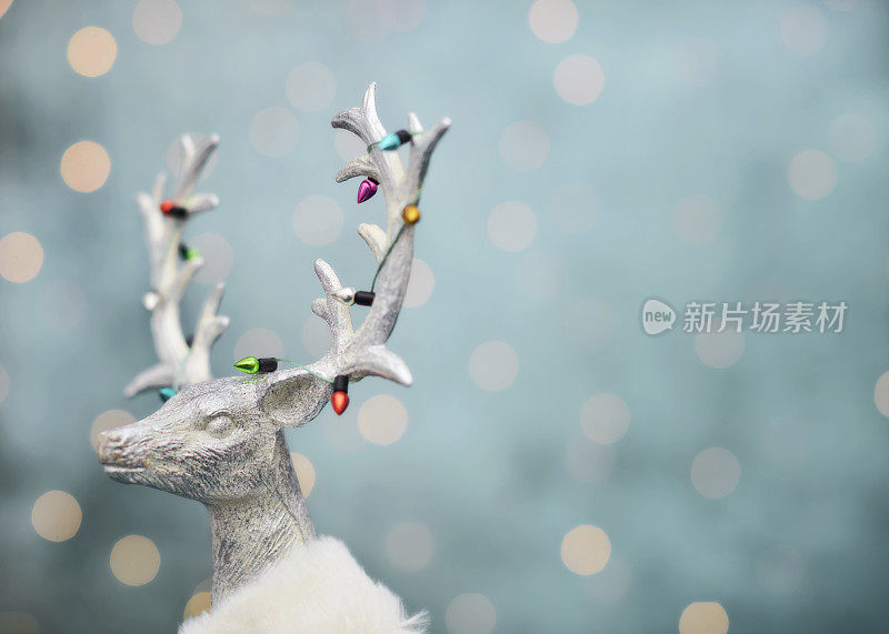 现代圣诞背景与银鹿戴着圣诞灯周围的鹿角。空间的文本