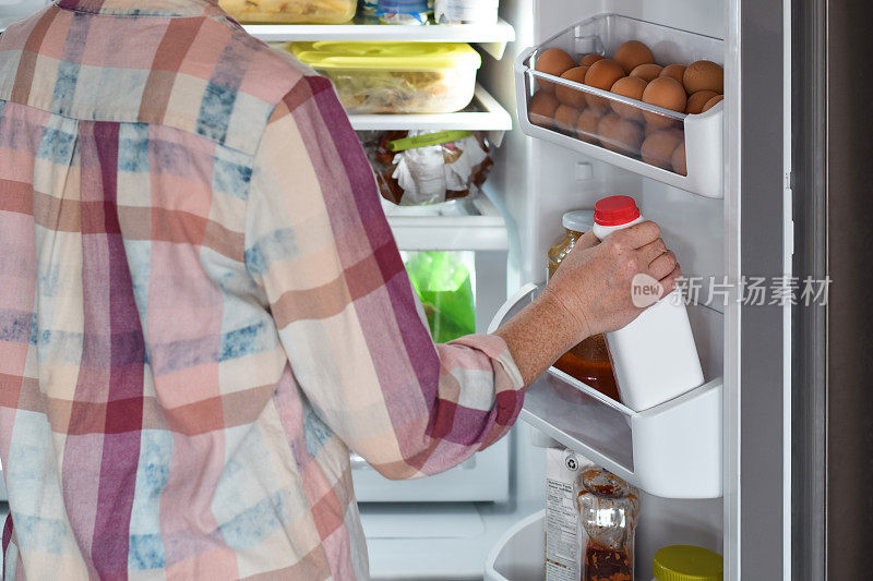 女人从冰箱里拿出一瓶酸奶或牛奶