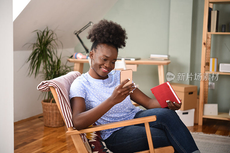 一个年轻的非洲女人在她的智能手机上阅读和发短信